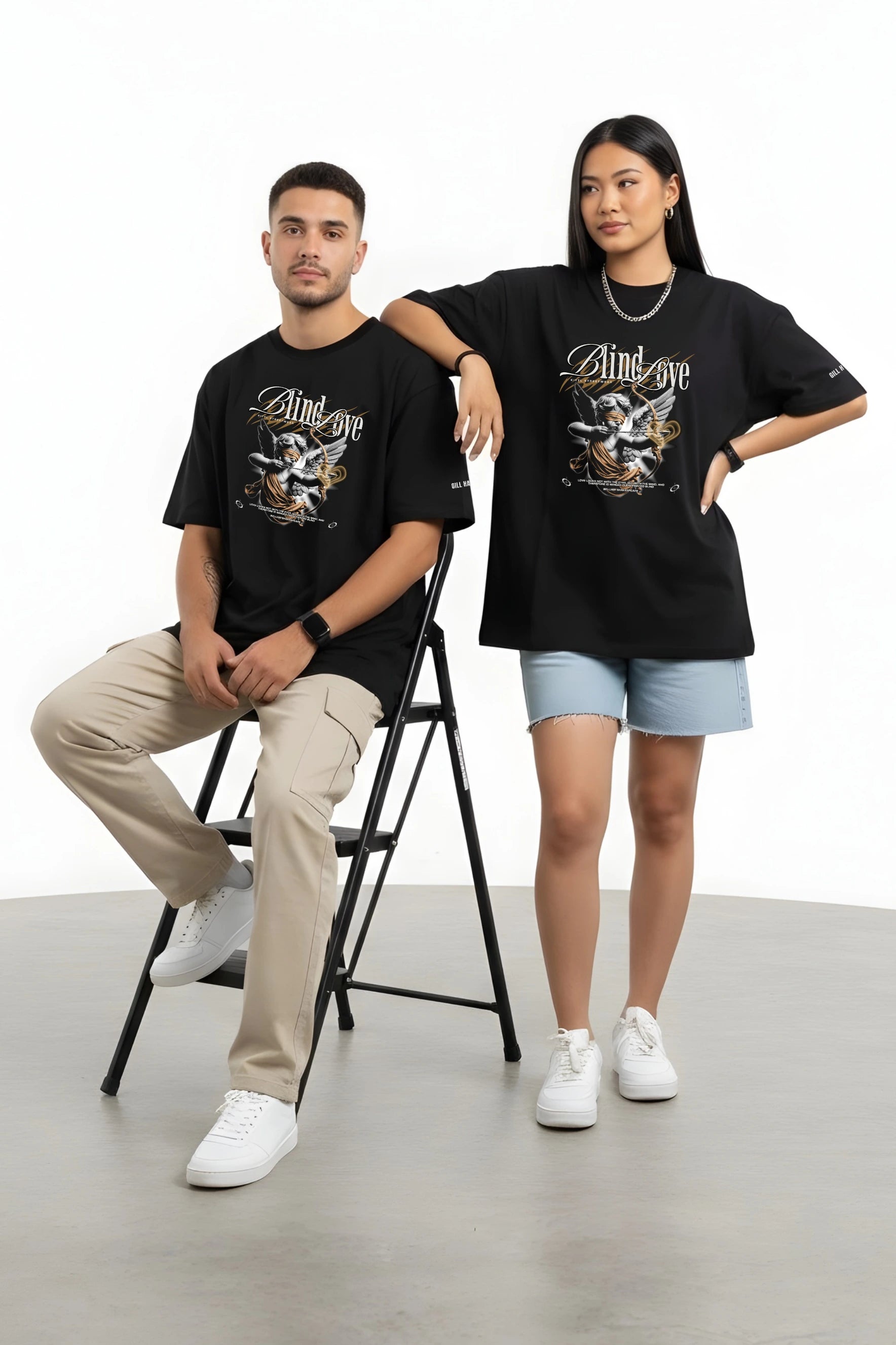 Two people wearing black t-shirts with graphic designs on a plain background