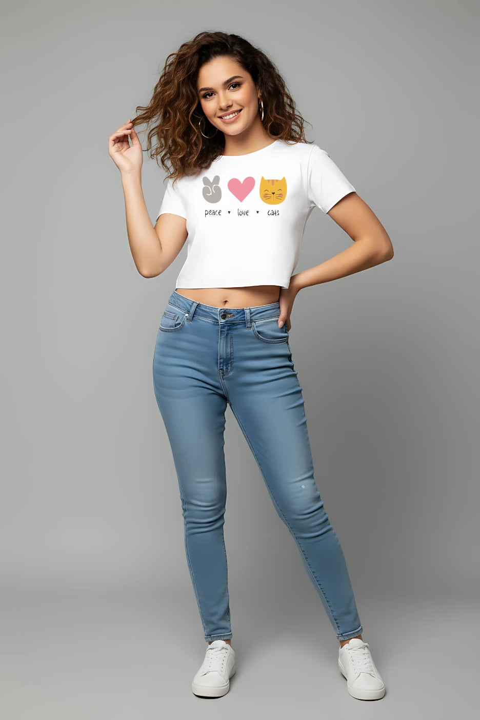 Woman wearing a white t-shirt with cat illustrations and blue jeans on a gray background