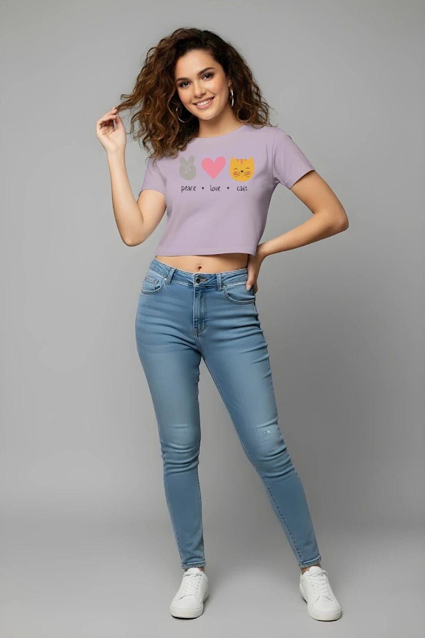 Woman wearing a light purple t-shirt with graphics and text, paired with blue jeans on a gray background